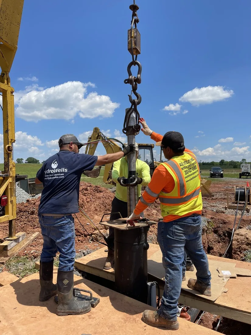 Crew guiding well casing with the hoist