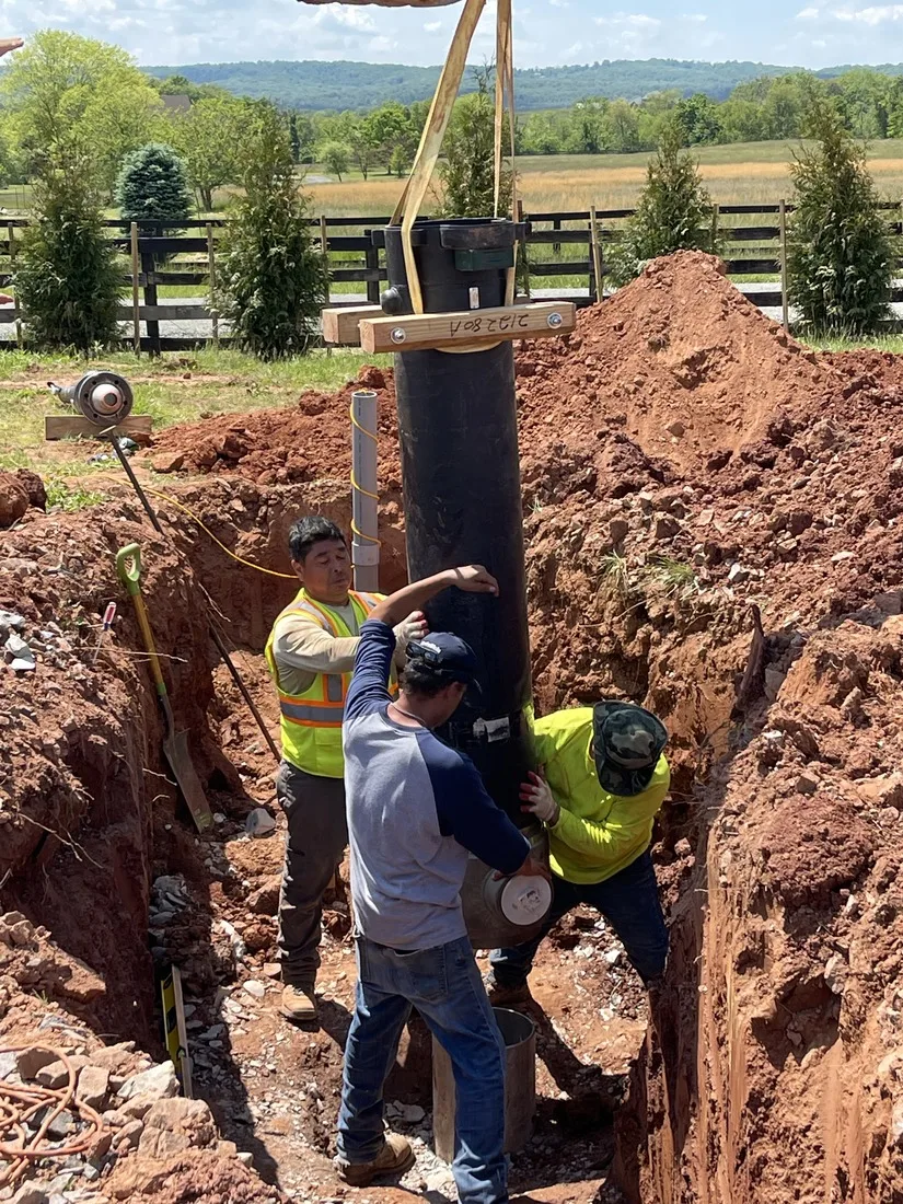 Crew setting steel well casing into a fresh borehole