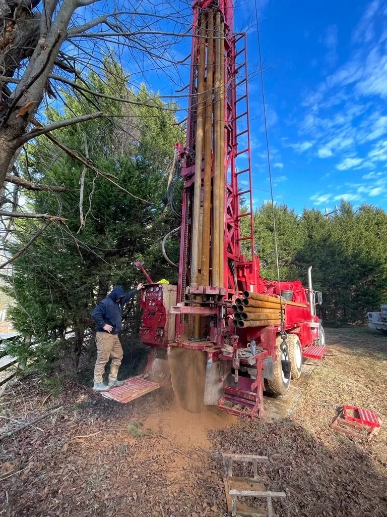 HydroWells drill rig working between mature trees